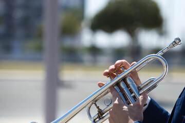 Detail of the hands of a trumpet player playing the musical instrument. The hand raises and lowers the pistons of the trumpet. October 1 st international day of music.