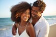 © Spencer - A young attractive black couple embracing on a summer beach.