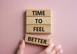 Time to feel better symbol. Wooden blocks with words Time to feel better. Businessman hand. Beautiful pink background. Medicine and Time to feel better concept. Copy space.