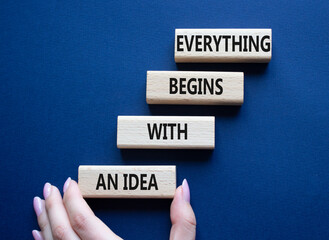 Everything begins with and Idea symbol. Concept words Everything begins with and Idea on wooden blocks. Beautiful deep blue background. Businessman hand. Business. Copy space.