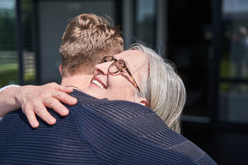 Cropped view of the smiling senior woman embracing her adult son