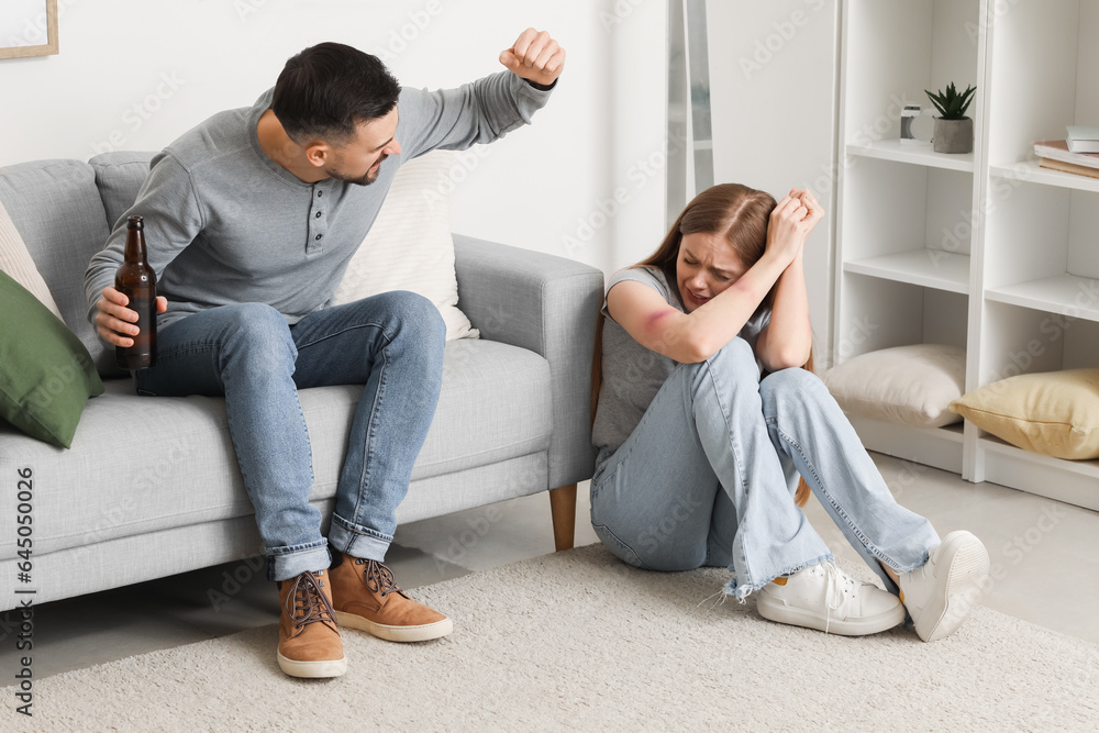 Bruised young woman and her drunk husband at home. Domestic violence concept