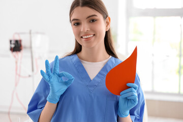 Wall Mural - Female nurse with paper blood drop showing OK in clinic