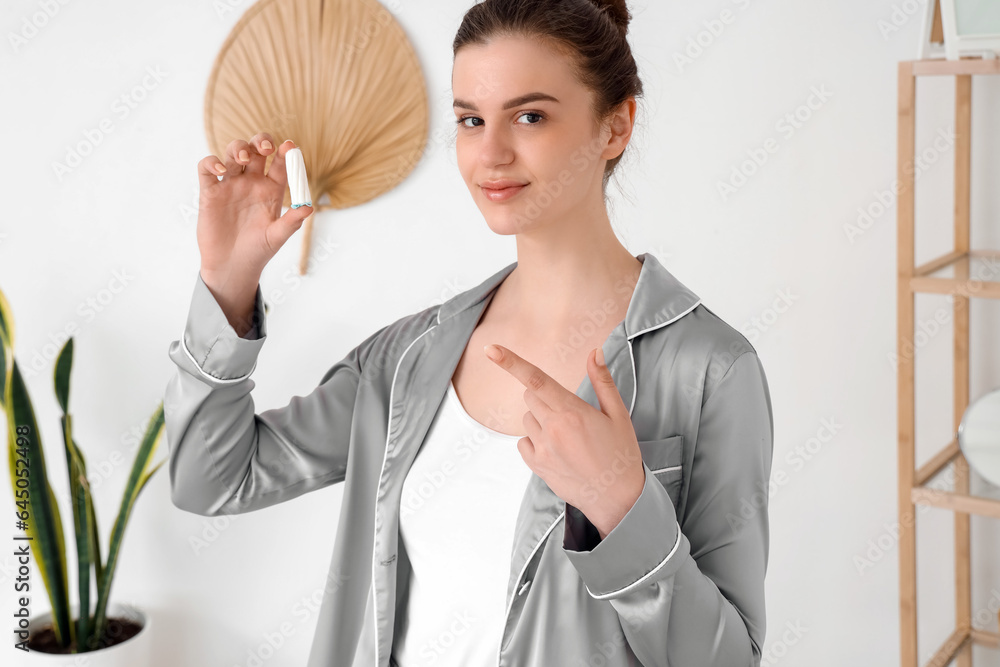 Young woman pointing at tampon in bathroom