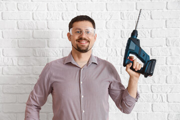 Canvas Print - Male builder with drill near white brick wall