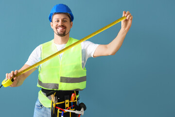 Canvas Print - Male builder with tape measure on blue background