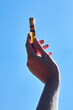 a glass perfume bottle in the hands of a woman against a blue sky