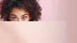 text space for advertising with funny part as portrait of afro american female model peeking over a colored panal