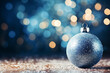Christmas ball on the snow against the backdrop of beautiful blue bokeh and falling snowflakes. Christmas and New Year background. Greeting  card with space for text. Festive Christmas decoration