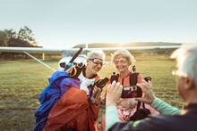 Senior Man Taking Pictures Of A Lesbian Couple After Skydiving And Completing Their Bucket List