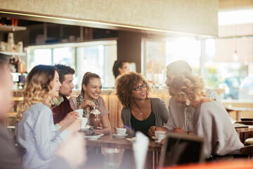 Young and diverse group of people talking and having coffee together in a cafe