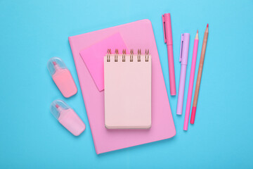 Wall Mural - Flat lay composition with pink notebooks and other school stationery on light blue background, space for text. Back to school