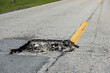 Dangerous pothole on american road surface. Ruined driveway in urgent need of repair