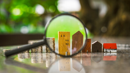 Wall Mural - Hand holding magnifying glass and looking at house model, house selection, real estate concept.	