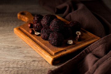 Wall Mural - Brigadeiro and hazelnuts on kitchen board on wooden background, close up