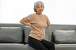 © Phushutter - Elderly asian woman sitting on the couch, back pain, osteoporosis.