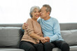 © makibestphoto - Affectionate senior Asian couple sharing warm embrace on the sofa, celebrating their enduring love and togetherness. Elderly husband and wife happy family