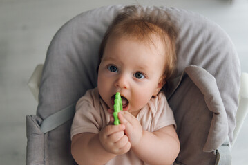 Cute close-up of baby lying in cradle and holding teething ring, adorable baby 5 month old baby