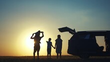 Family Traveling By Car. Family Watching The Sunset Silhouette Next To The Car In The Park. Happy Family Kid Dream Concept. People In The Park. Lifestyle Family Car Camping Resting In Nature