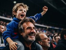 French Father And Son In Stands, Filled With Enthusiastic Supporters Of Rugby Or Football Team Wearing Blue Clothes To Support National Sports Team