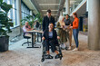 © .shock - A diverse group of business colleagues is having fun with their wheelchair-using colleague, demonstrating their attention and inclusivity in the workplace
