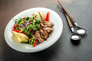 Wall Mural - Sliced grilled beef steak with green leaves salad on a dark background. banner, menu, recipe place for text, top view