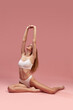 © Lustre Art Group  - Charming young thin sportive woman in white cotton underwear sitting on floor over pink background. recretion, relaxing