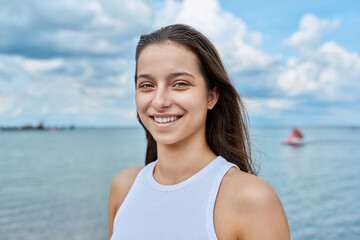 Wall Mural - Portrait of smiling teenage girl outdoor on sea background