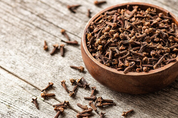 Wall Mural - Dry cloves in wooden bowl on rustic table, fresh herb spice concept 