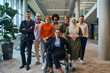 © .shock - In a spacious and modern startup office, a diverse group of business colleagues, including a colleague in a wheelchair, collaborates and interacts, exemplifying inclusivity, diversity, and teamwork in