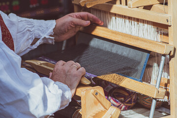 A craftswoman working on an ancient wooden weaving loom in a arts and crafts fair in Vilnius, Lithuania 