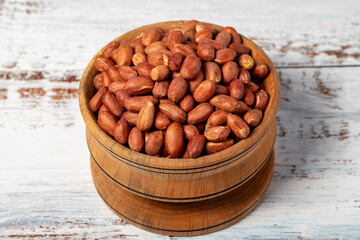 Wall Mural - Peanuts in wooden bowl. Peanuts in shell on white wood background