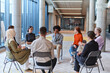 © .shock - A diverse group of young business entrepreneurs gathered in a circle for a meeting, discussing corporate challenges and innovative solutions within the modern confines of a large corporation