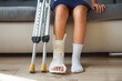 Child with a cast leg and crutches sitting on the sofa