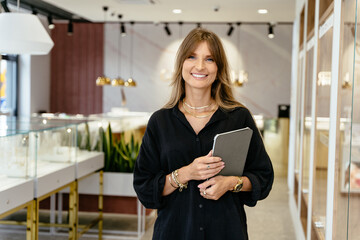 Positive friendly mature middle age beautiful female business owner in a jewelry shop, portrait.