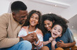 © Wesley/peopleimages.com - Family, parents and children on sofa with smile for bonding, healthy relationship and love. Home, living room and happy mother, father and kids laughing together for happiness, joy and relax on couch