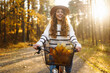 canvas print picture - Happy active woman in stylish clothes rides a bicycle in an autumn park at sunset. Outdoor portrait. Beautiful woman enjoying nature. Active lifestyle.