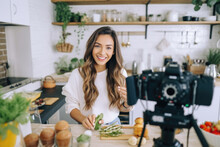A Young Woman Food Blogger Cooking Salad In Front Of Smartphone Camera While Recording Vlog Video And Live Streaming At Home In Kitchen.