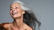 © IBEX.Media - Portrait of smiling beautiful old woman with gray long hair in dynamic motion on grey background