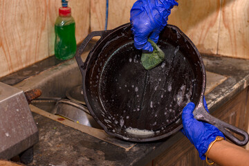 Woman's hands to cleaning cast iron pan with dish washer and scrubber.