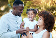 © Anela/peopleimages.com - Diversity, love and children with a family laughing outdoor in a garden together for support, comedy or bonding. Kids, smile or kids with a happy mother, father and daughter in a park during summer