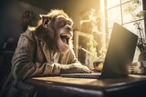 The monkey is sitting at his laptop and laughing.