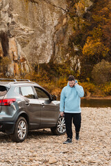 Poster - man at the rocky beach in mountain river near car