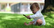 © Marco - Adorable baby sitting outside in home lawn holding stick. Cute infant toddler playing with stick outdoors