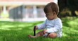 © Marco - Adorable baby sitting outside in home lawn holding stick. Cute infant toddler playing with stick outdoors