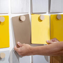 Wall Mural - Designer hands compare colorful laminate sheets on material swatch wall display in material library. Choosing color board from collection for interior architecture and furniture finishing design