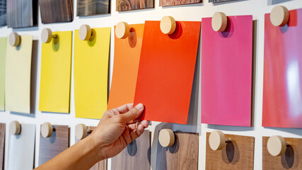 Wall Mural - Designer hand picking colorful laminate sheet on material swatch wall display in material library. Choosing color board from collection for interior architecture and furniture finishing design