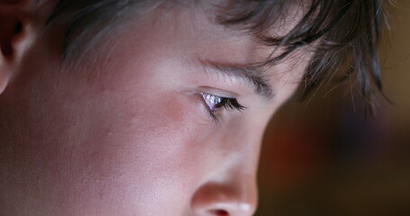 Wall Mural - Boy eyes looking at device screen. Child staring at bright blue display closeup face