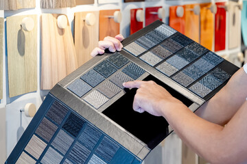 Wall Mural - designer hand pointing on fabric tile carpet samples catalog in material library. choosing rug floor