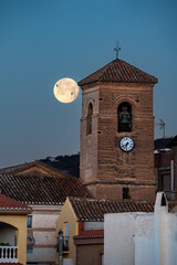 Full moon with the silhouette of two birds behind the bell tower of the church of Lobres, Salobreña, Granada,